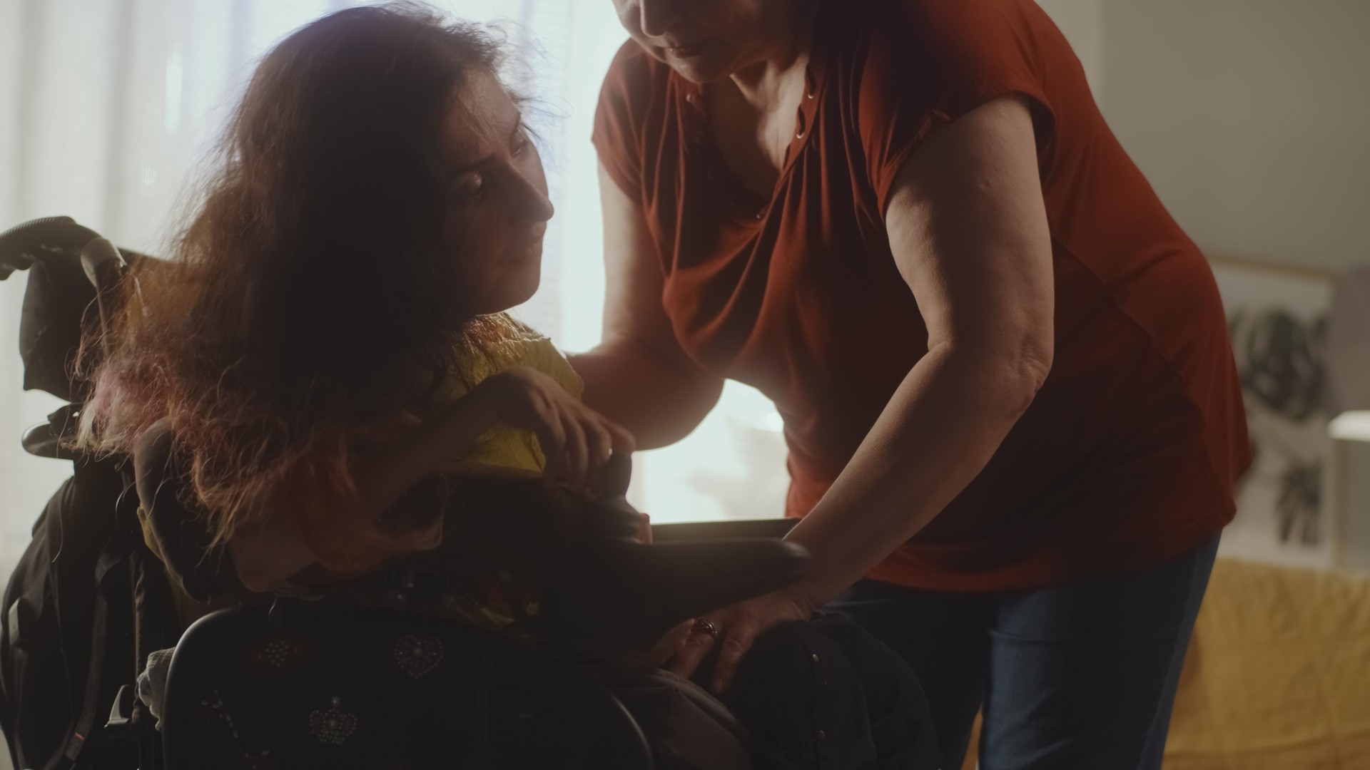 Caregiver helping woman to sit in a wheelchair